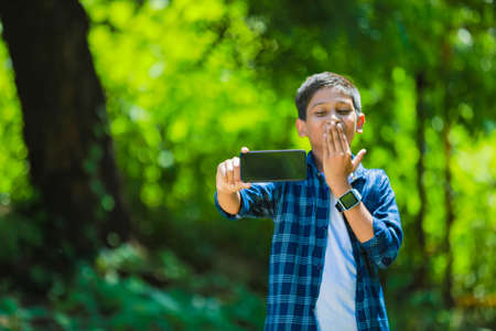 childhood, technology and people concept - indian cute school boy showing smartphone with blank screenの写真素材