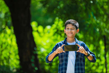 technology and people concept - smiling teenage boy in blue shirt showing smartphone with blank screenの写真素材