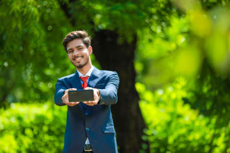 Happy businessman pointing finger on blank smartphone screenの写真素材