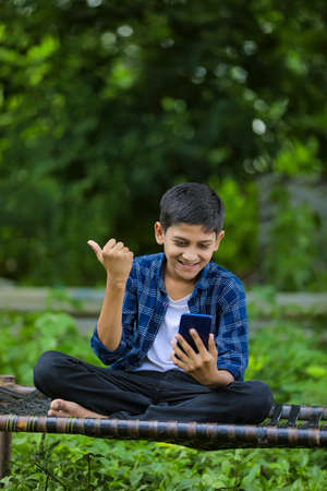 Cute indian little child excited with using smartphoneの写真素材