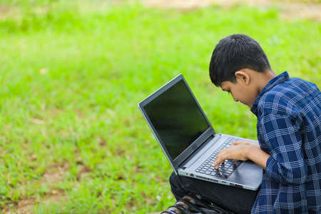 Technology concept : Cute indian little school boy using laptop