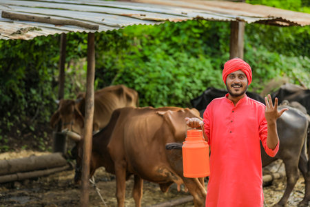 Indian farmer holding milk bottle in hand at dairy farmの写真素材