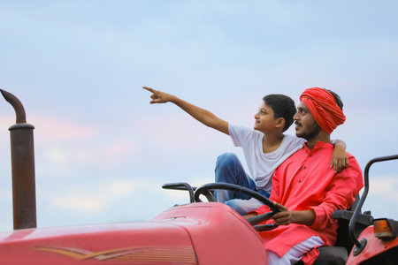 Indian farmer and cute little child enjoying tractor ride in agriculture fieldの写真素材