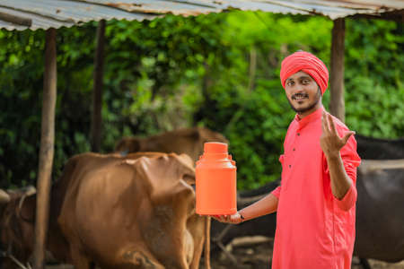 Indian farmer holding milk bottle in hand at dairy farmの写真素材