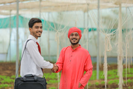 Young indian agronomist discuss with farmer at greenhouseの写真素材