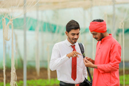 Young indian agronomist discuss with farmer at greenhouseの写真素材