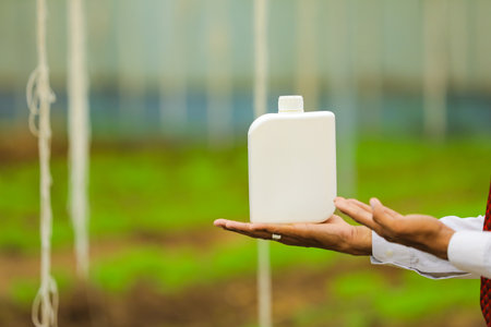 Young agronomist holding bottle in hand at greenhouseの写真素材