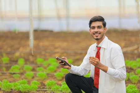 Technology and people concept, Young indian agronomist with tablet at greenhouseの写真素材