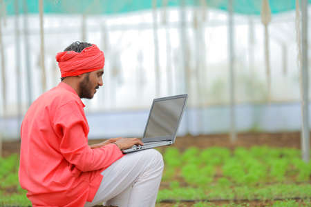 Young indian farmer using laptop at greenhouse or polyhouseの写真素材