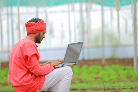 Young indian farmer using laptop at greenhouse or polyhouseの写真素材