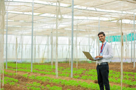 Young agronomist or banker with laptop at greenhouse