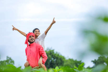 Indian farmer playing with his child at green field
