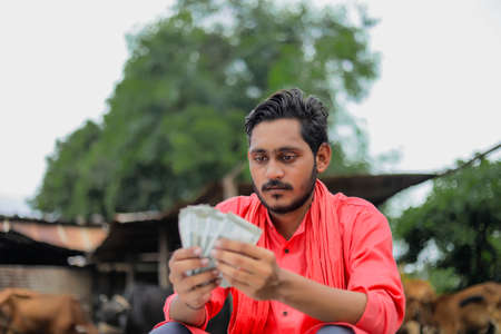 Young indian farmer counting money