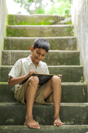 Indian child writing A B C D alphabet on Chalkboard