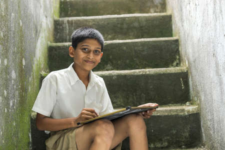Indian child writing A B C D alphabet on Chalkboardの写真素材