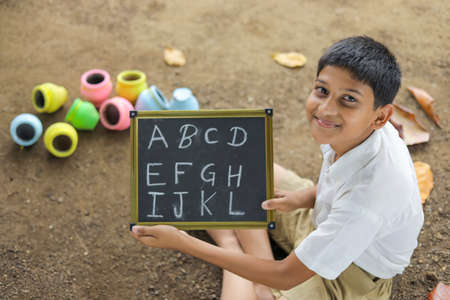 Indian child writing A B C D alphabet on Chalkboardの写真素材