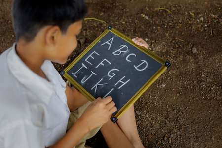 Indian child writing A B C D alphabet on Chalkboardの写真素材