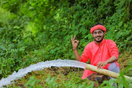 indian farmer with water flow from pipe at fieldの写真素材