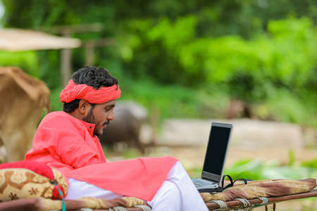 technology concept : Young indian farmer using laptop at homeの写真素材