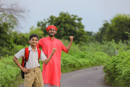 indian farmer with his child on road side and asking lift for going to homeの写真素材