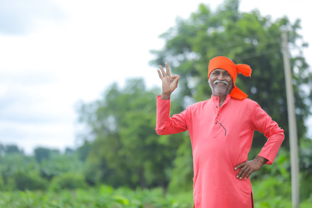 Happy indian farmer standing and smile at fieldの写真素材
