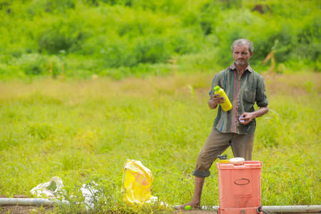 indian labour liquid fertilizer mixing in bucket at field