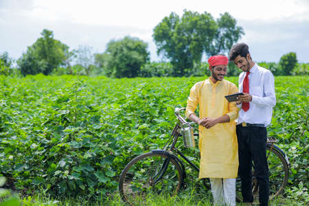 Young indian agronomist or banker showing some information to farmer in smartphoneの写真素材