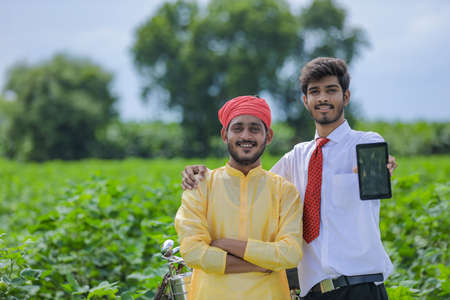 Young indian agronomist or banker showing smart phone with farmer at cotton fieldの写真素材