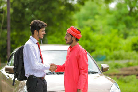 Young indian farmer and banker shake hands after a new car purchasingの写真素材
