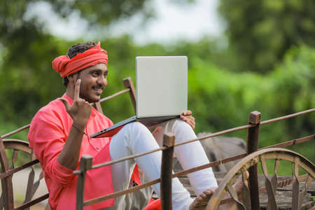 Technology concept : Young indian farmer using laptopの写真素材