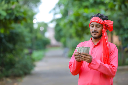 young indian farmer counting money at home