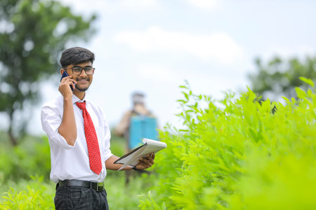 Indian agronomist talking on mobile phone at fieldの写真素材