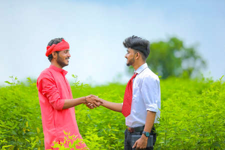 Young agronomist shack hand with indian farmer at fieldの写真素材