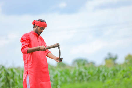 Young indian farmer hard working with farm equipment in his field