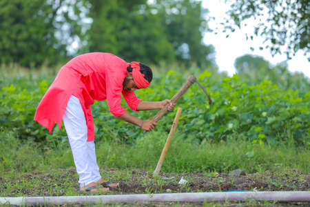 Young indian farmer hard working with farm equipment in his fieldの写真素材
