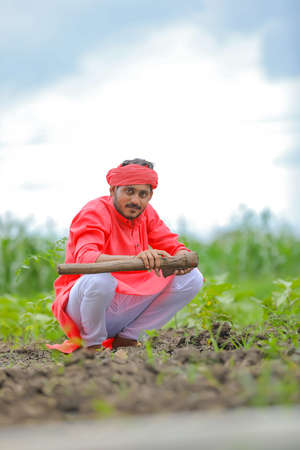 Young indian farmer hard working with farm equipment in his field