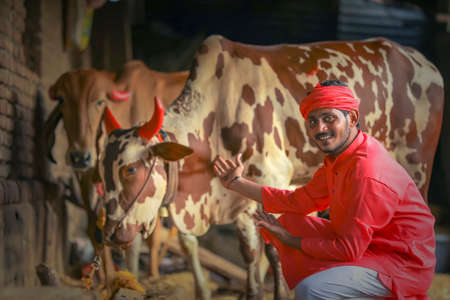young indian farmer standing with farm cattle animal
