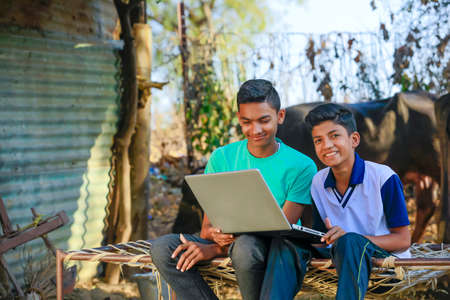 Cute little Indian/Asian boy studying or playing game with laptop computer