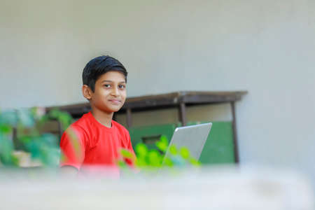 Cute little Indian/Asian boy studying or playing game with laptop computer