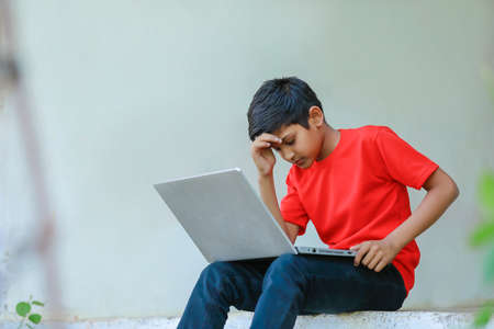 Depressed or stress Indian Little Boy Using a Laptopの写真素材