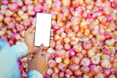 Young indian farmer showing smartphone screen at agriculture field