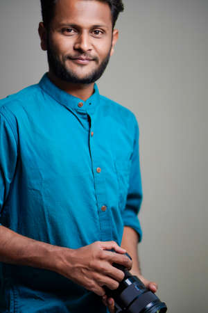 Young Indian man standing on white background.