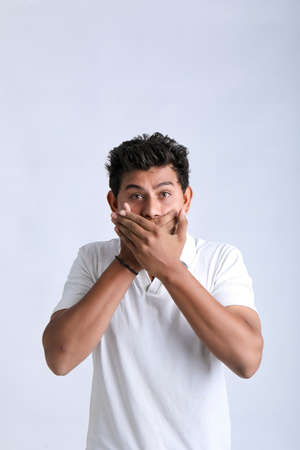 Young indian man shocked and covering mouth with hand.