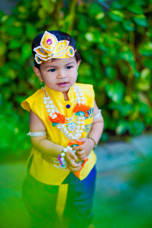 happy Janmashtami Greeting Card showing Little Indian boy posing as Shri krishna or kanha/kanhaiya with Dahi Handi picture and colourful flowers.の写真素材