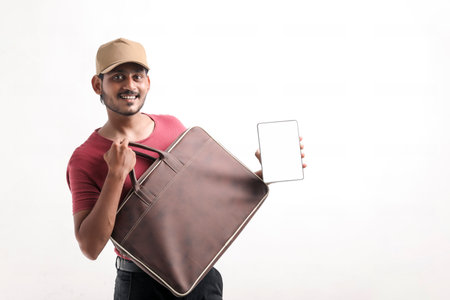 Portrait of a excited happy young delivery man in cap standing over white background. Looking camera...