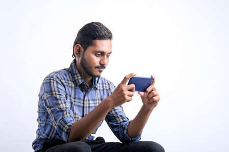Young indian man using smartphone over white background.の写真素材