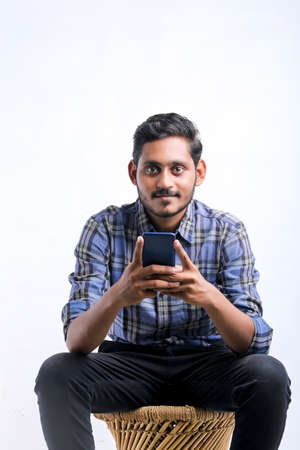 Young indian man using smartphone over white background.