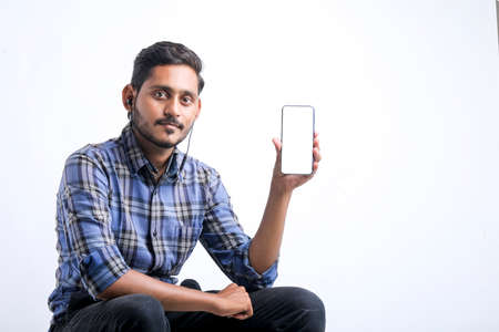 young indian man showing Smartphone over white background.