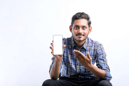 young indian man showing Smartphone over white background.の写真素材