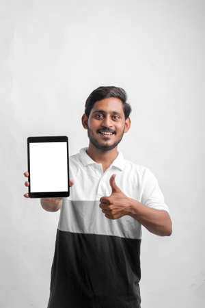 young indian man showing tablet over white background.の写真素材